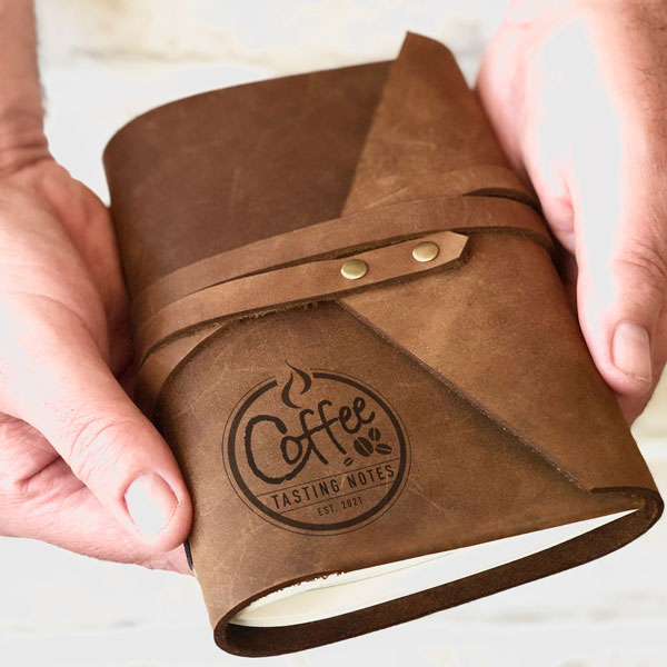 Leather personalised coffee tasting journal, wrap style, held in hand