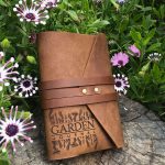 Leather personalised gardeners journal, wrap style, leather journal surrounded by garden flowers