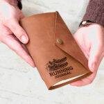 An image with two hands holding a leather running journal