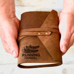 Two hands holding a leather running journal